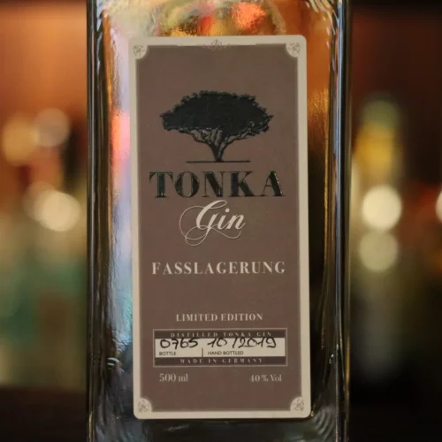 Tonka Gin Fasslagerung Flasche Nahaufnahme. Im Hintergrund unscharfe Lichter.